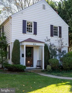 a view of a white house next to a yard with palm trees