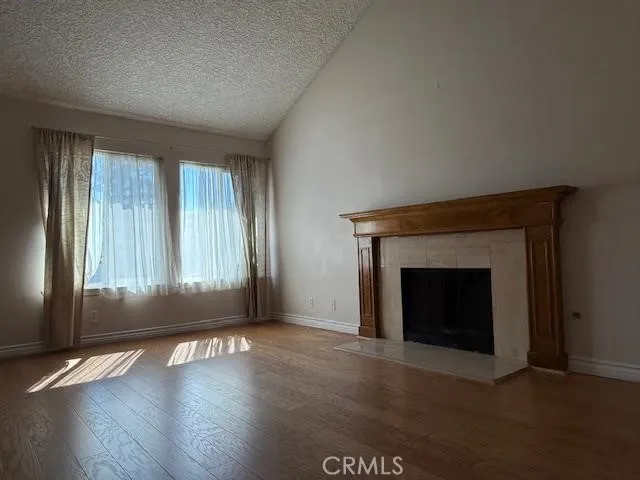 an empty room with wooden floor fireplace and windows