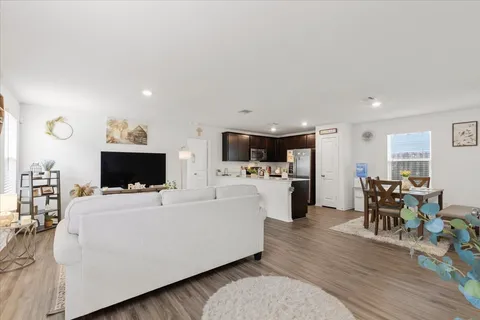 a living room with furniture a flat screen tv and kitchen view