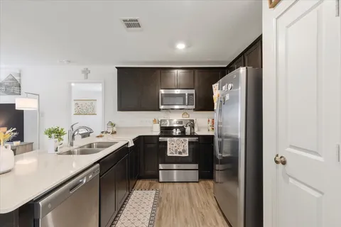 a kitchen with stainless steel appliances granite countertop a refrigerator a sink a stove a microwave and island