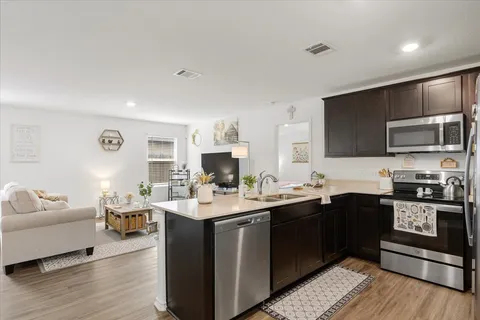 a open kitchen with stainless steel appliances granite countertop a sink dishwasher stove and oven with wooden floor