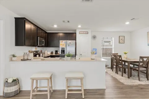 a kitchen with stainless steel appliances granite countertop a table chairs microwave and sink