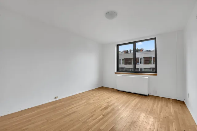 an empty room with wooden floor and mirror