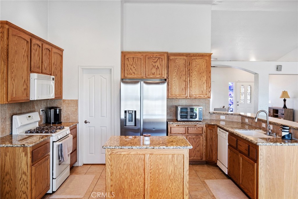 11025 El Esteban Road Phelan, CA 92371 - Photo 15 of 54 a kitchen with kitchen island wooden cabinets a stove a sink and a refrigerator