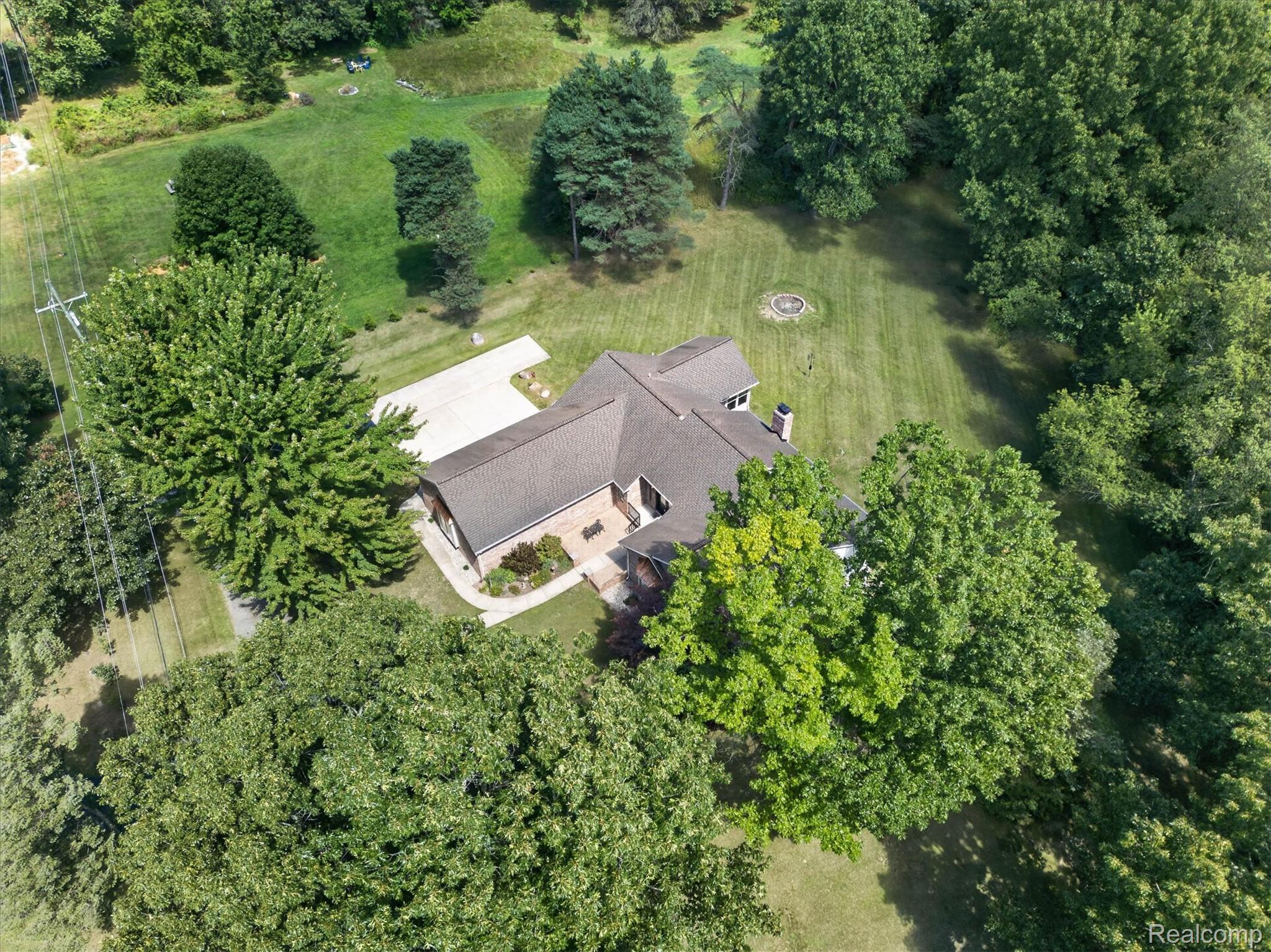 4037 Chilson Road Howell, MI 48843 - Photo 60 of 69 Residential structure with a dark shingle roof, surrounded by mature trees and expansive green space