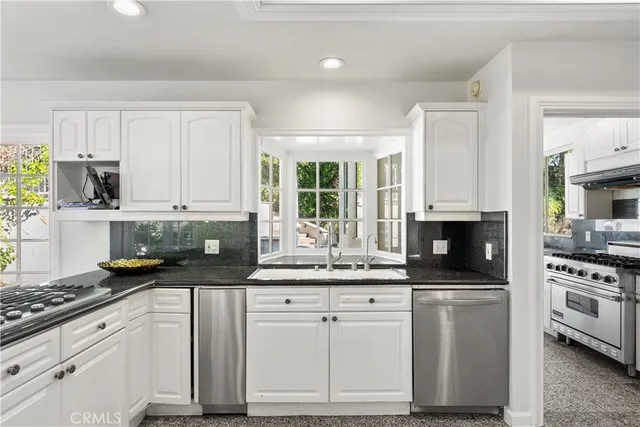 a kitchen with granite countertop a sink a stove and cabinets