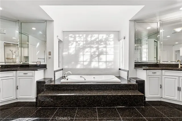 a large white kitchen with a large window a sink and stainless steel appliances