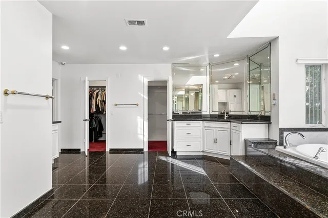 a large white kitchen with kitchen island a sink stainless steel appliances and cabinets