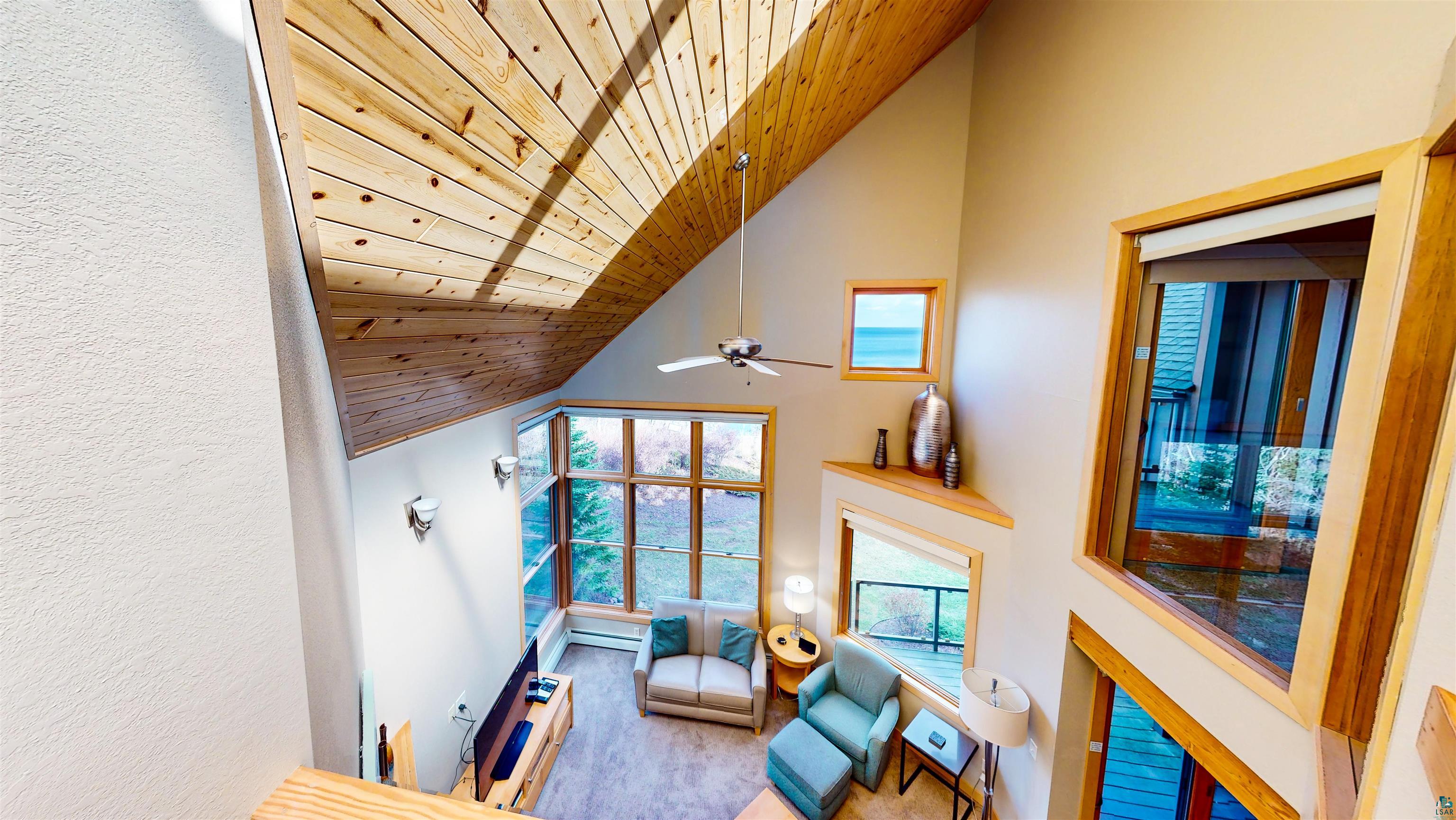 40 Surfside Drive, Unit 5D Tofte, MN 55615 - Photo 18 of 37 Vaulted ceiling with natural wood paneling, featuring a ceiling fan and upper wall sconces