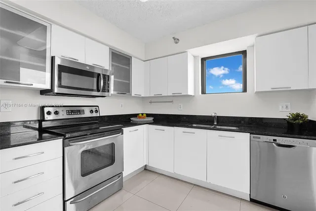 a kitchen with granite countertop white cabinets and stainless steel appliances