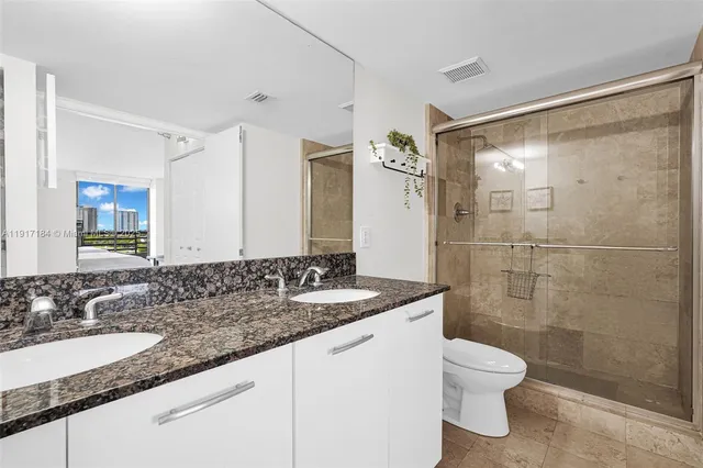 a bathroom with a granite countertop sink toilet and shower