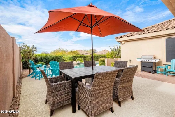 a patio with a table and chairs under an umbrella