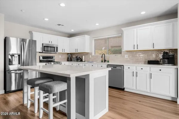 a kitchen with stainless steel appliances kitchen island granite countertop a table chairs sink refrigerator and cabinets
