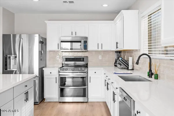 a kitchen with stainless steel appliances a sink cabinets and a wooden floor