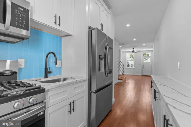 a kitchen with stainless steel appliances granite countertop a refrigerator a stove and a sink with wooden floor