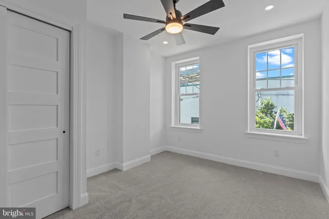 an empty room with windows and a chandelier fan
