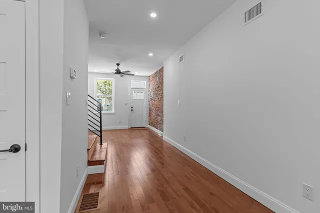 a view of a hallway with wooden floor and staircase