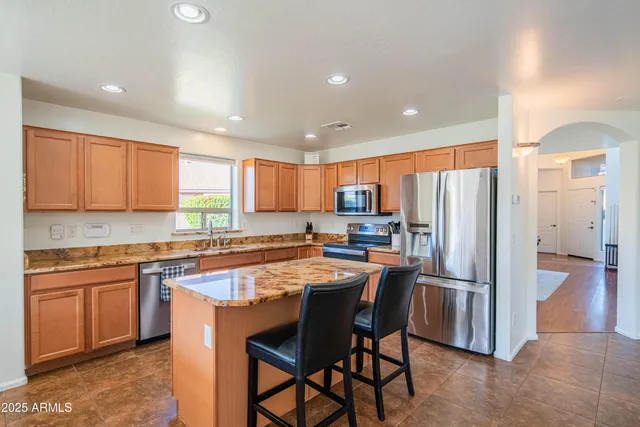 a kitchen with stainless steel appliances granite countertop a table chairs sink refrigerator and cabinets