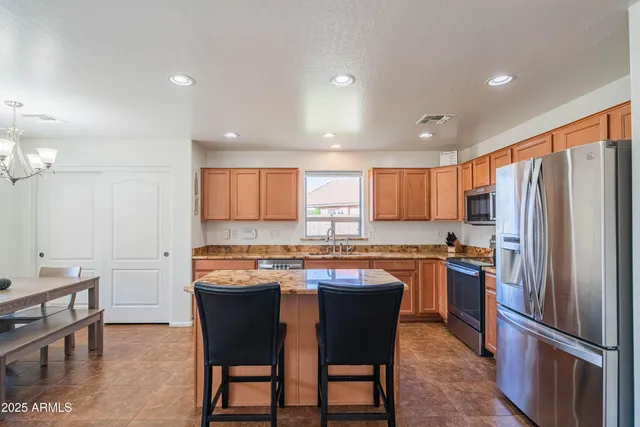 a kitchen with stainless steel appliances granite countertop a table chairs sink refrigerator and cabinets