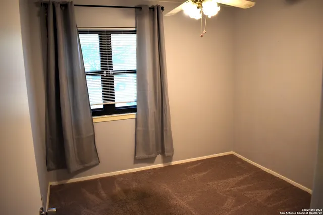 a view of a room with a ceiling fan and a window