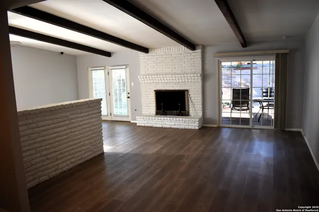 a view of a livingroom with wooden floor and a fireplace