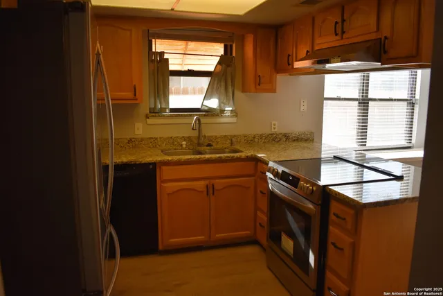 a kitchen with stainless steel appliances granite countertop a sink stove and cabinets