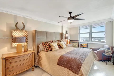 a bedroom with a large bed and a chandelier fan