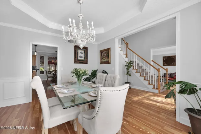 a view of a dining room with furniture a chandelier and wooden floor