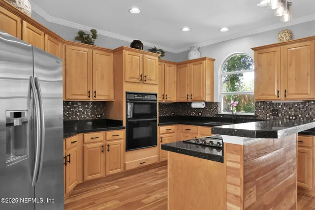 a kitchen with stainless steel appliances granite countertop a refrigerator a stove and a sink
