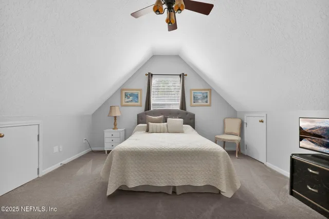 a spacious bedroom with a bed a chandelier and a window