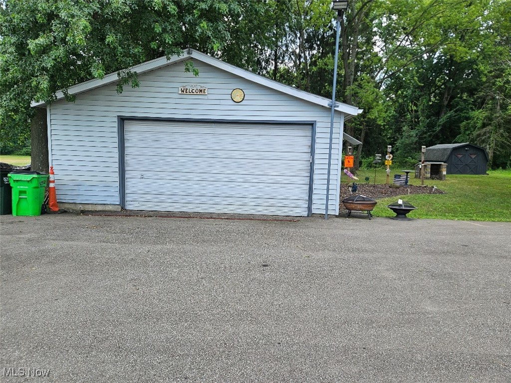 Detached garage featuring view of scattered trees