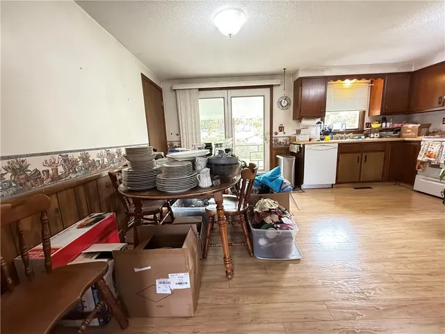 a kitchen with a refrigerator a stove top oven a sink dishwasher and wooden cabinets with wooden floor