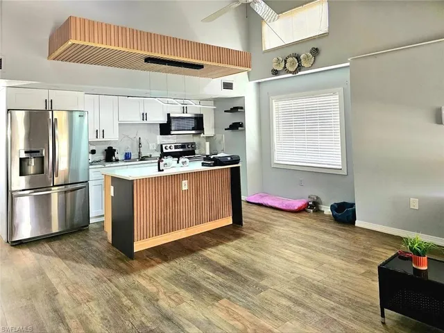 a kitchen with stainless steel appliances kitchen island granite countertop a stove a sink and a refrigerator