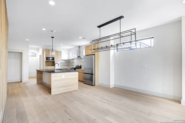 a kitchen with kitchen island a refrigerator and white cabinets
