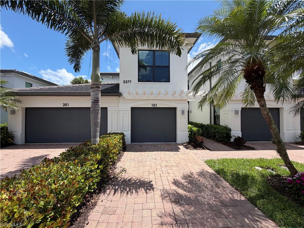 2377 Ravenna Boulevard, Unit 101 Naples, FL 34109 - Photo 1 of 19 a front view of a house with a yard and a garage