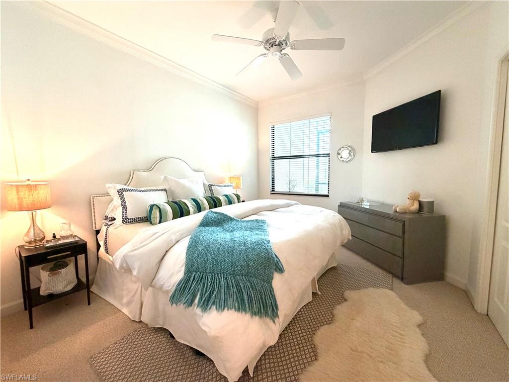 2377 Ravenna Boulevard, Unit 101 Naples, FL 34109 - Photo 16 of 19 a spacious bedroom with a bed and a flat screen tv