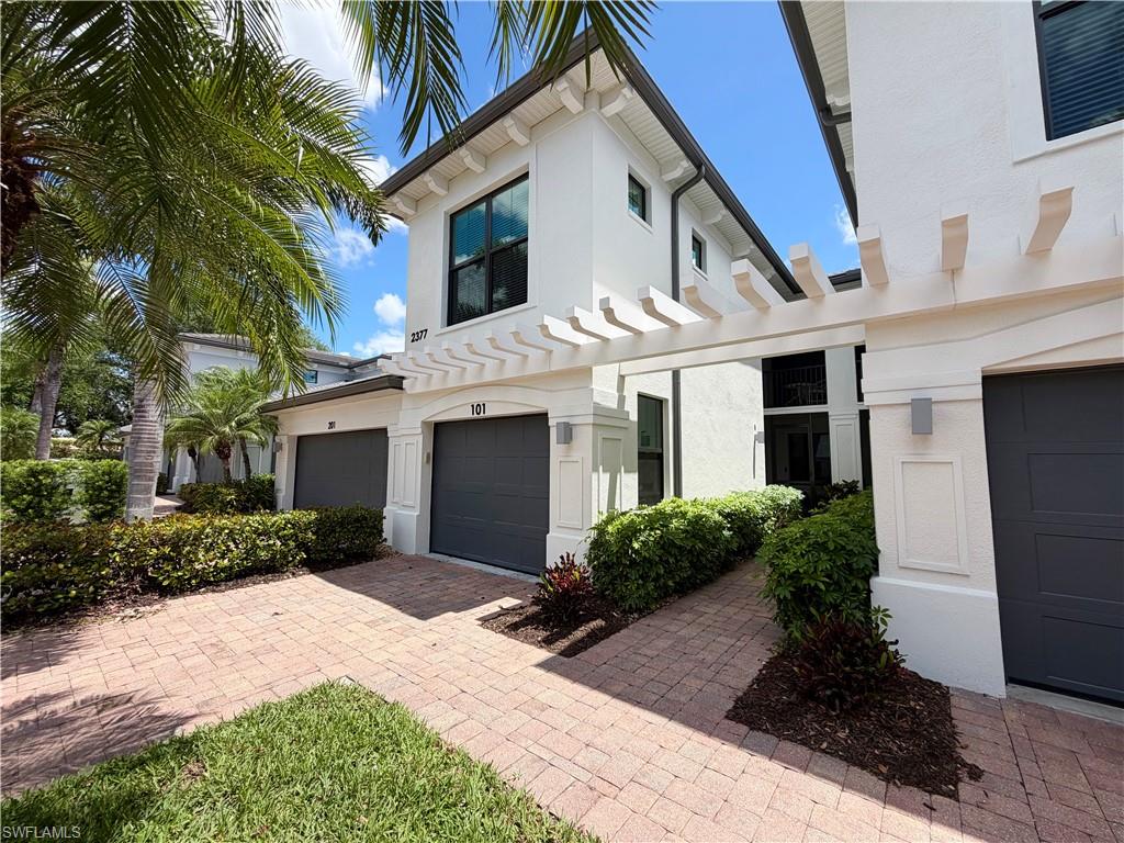 2377 Ravenna Boulevard, Unit 101 Naples, FL 34109 - Photo 2 of 19 a front view of a house with a garden