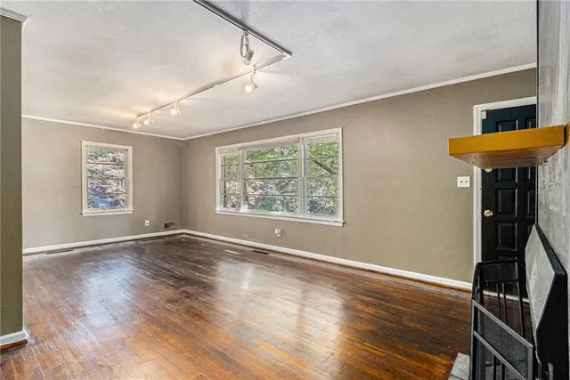 a view of an empty room with window and wooden floor
