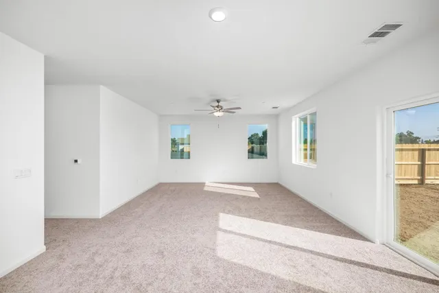 an empty room with windows and chandelier fan