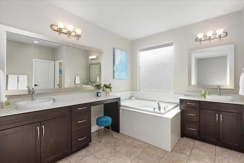 a bathroom with a tub a sink double vanity and a mirror