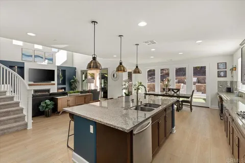 a kitchen with stainless steel appliances kitchen island granite countertop a table chairs and a stove