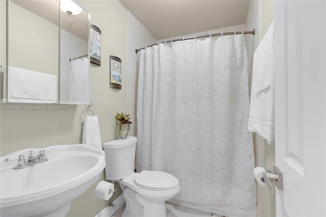 a white toilet sitting next to a bathroom sink and shower