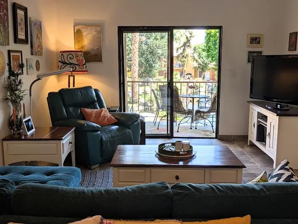 a living room with furniture a flat screen tv and a floor to ceiling window