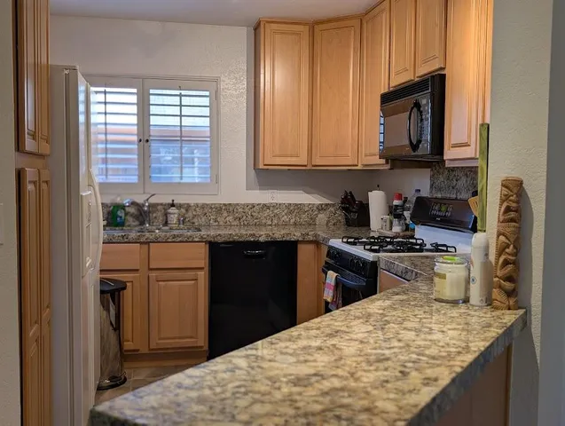 a kitchen with granite countertop wooden cabinets and a stove top oven