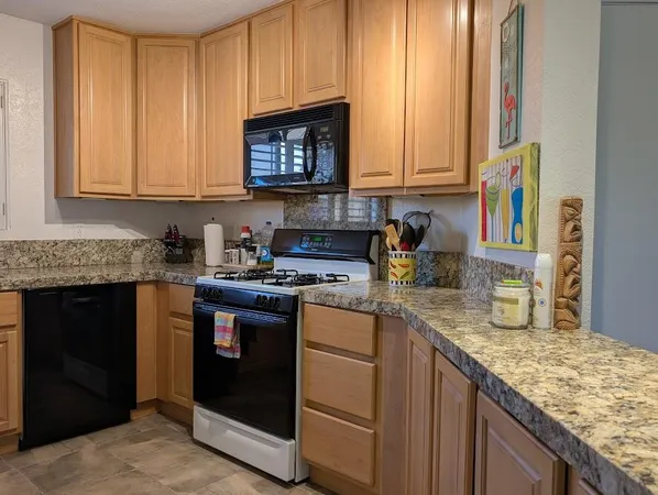 a kitchen with granite countertop stainless steel appliances a stove a sink and a microwave