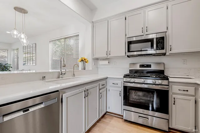 a kitchen with white cabinets stainless steel appliances and sink