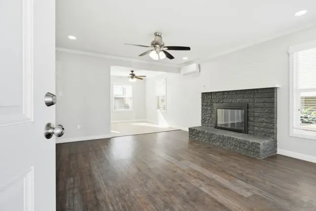 an empty room with wooden floor fireplace and windows