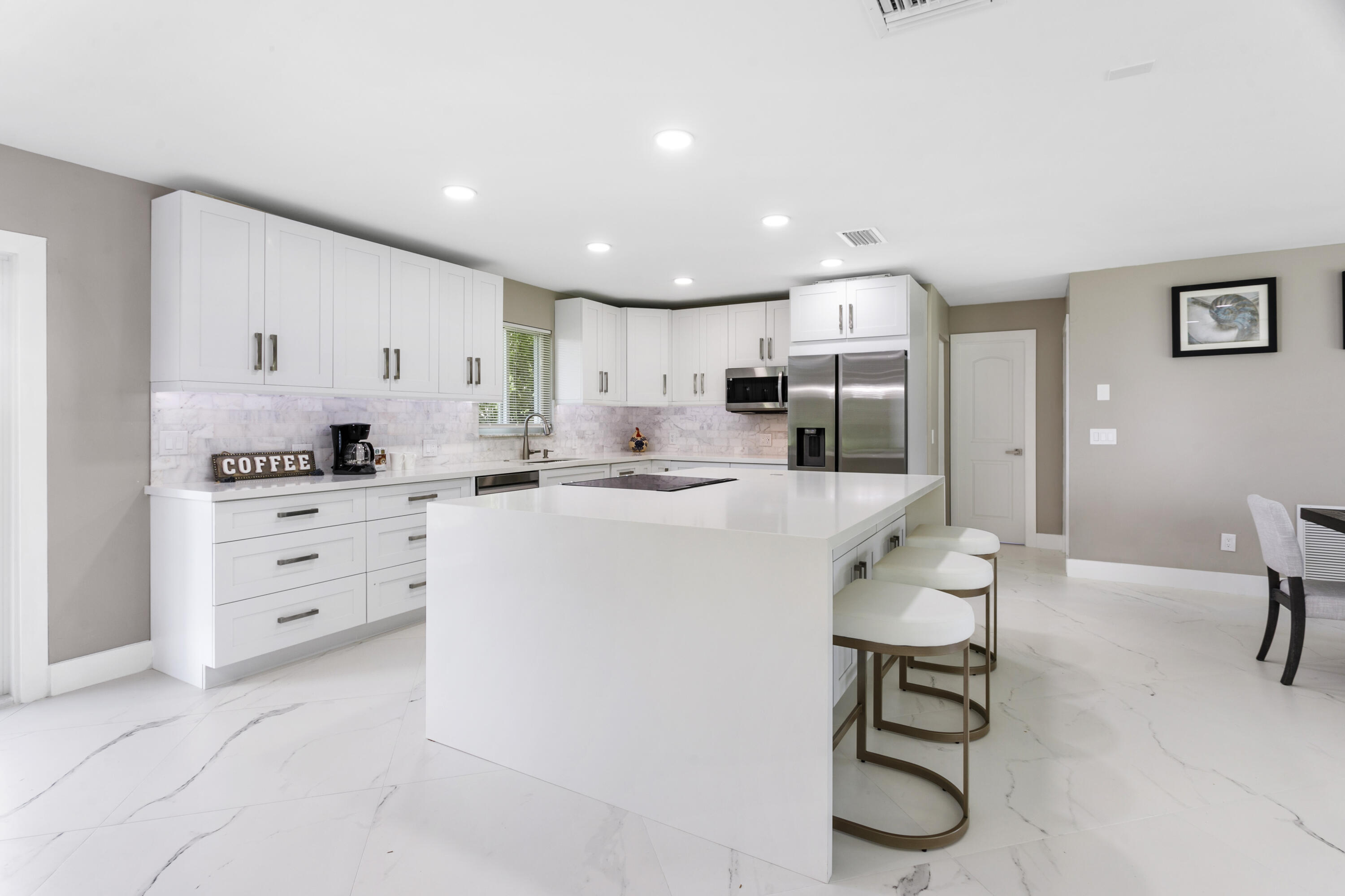 5200 Club Road Haverhill, FL 33415 - Photo 7 of 33 a kitchen with white cabinets and stainless steel appliances