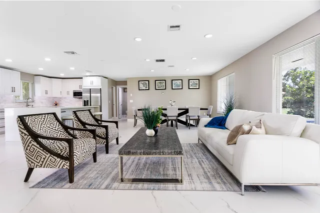 a kitchen with stainless steel appliances a sink a stove a refrigerator with white cabinets and wooden floor