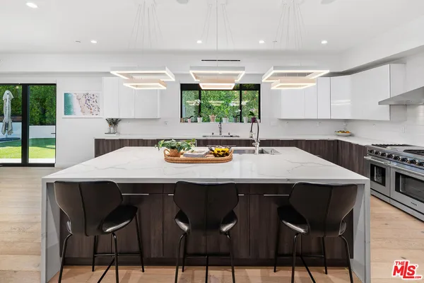 a kitchen with stainless steel appliances kitchen island granite countertop a table chairs sink and cabinets